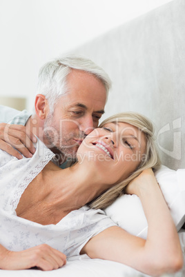 Mature man kissing womans cheek in bed