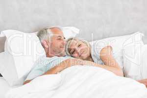 Loving mature man and woman lying in bed