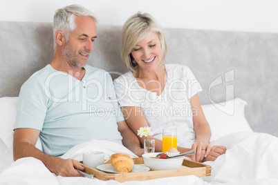 Happy couple having breakfast in bed