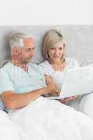 Mature couple using laptop in bed