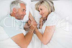 Loving mature man and woman lying in bed