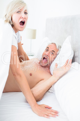 Portrait of mature couple shouting in bed