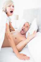 Portrait of mature couple shouting in bed