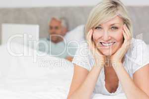 Happy mature woman with man using laptop in bed