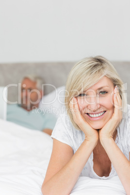 Happy woman with man using laptop in bed