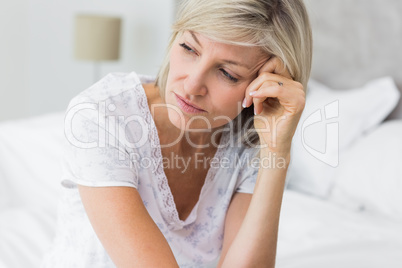 Tensed mature woman sitting in bed