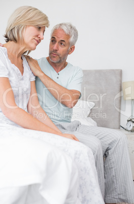 Man consoling tensed woman in bed Man consoling tensed woman in bed