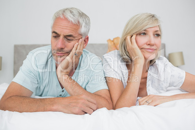 Closeup of displeased mature couple lying in bed