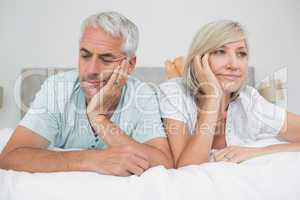 Closeup of displeased mature couple lying in bed