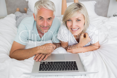 Relaxed mature couple using laptop in bed Relaxed mature couple using laptop in bed