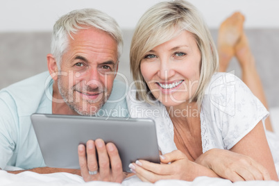 Smiling couple using digital tablet in bed Smiling couple using digital tablet in bed