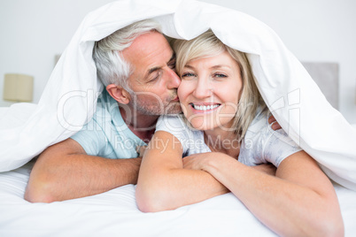 Closeup of mature man kissing womans cheek in bed