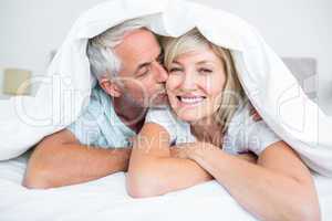 Closeup of mature man kissing womans cheek in bed