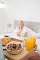 Woman sitting in bed with breakfast in foreground