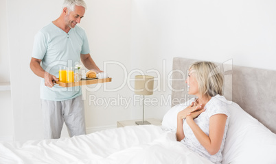 Man serving woman breakfast in bed