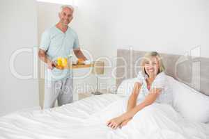 Man serving woman breakfast in bed