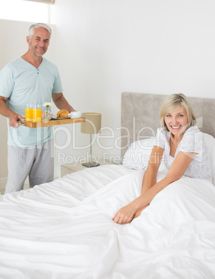 Man serving woman breakfast in bed