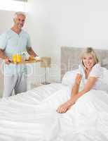 Man serving woman breakfast in bed