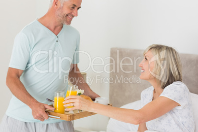 Man serving woman breakfast in bed