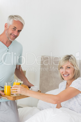 Man serving woman breakfast in bed