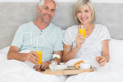 Happy mature couple having breakfast in bed