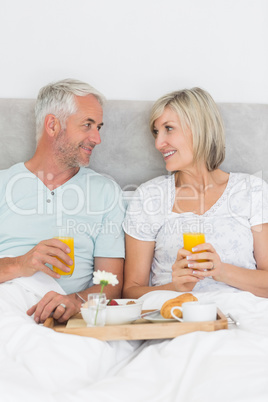 Happy mature couple having breakfast in bed