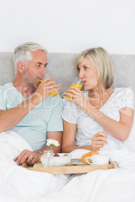 Happy mature couple having breakfast in bed