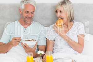 Happy couple having breakfast in bed