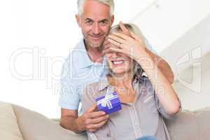 Smiling mature man surprising woman with a gift