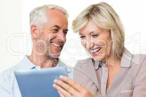 Closeup of cheerful mature couple using digital tablet