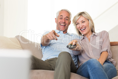 Cheerful couple watching tv at home