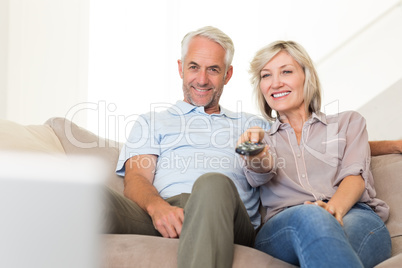 Happy couple watching tv on sofa