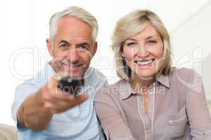 Happy mature couple watching tv at home