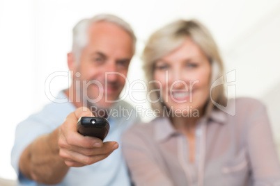 Blurred mature couple watching tv at home