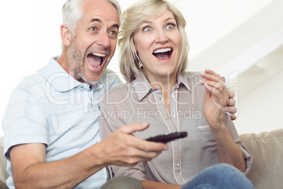 Cheerful couple watching tv on sofa