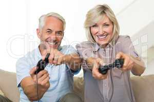 Cheerful mature couple playing video game on sofa