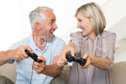 Cheerful mature couple playing video game on sofa