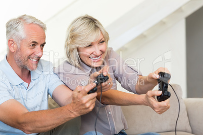 Cheerful mature couple playing video game on sofa