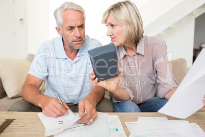 Concentrated mature couple with bills and calculator at home