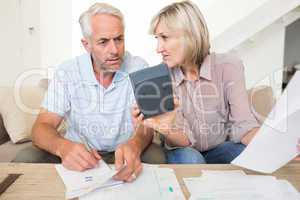 Concentrated mature couple with bills and calculator at home