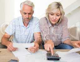 Concentrated mature couple with bills and calculator at home