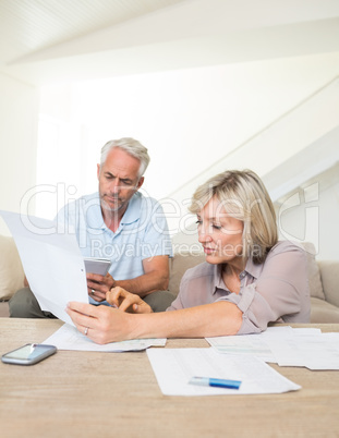 Concentrated mature couple with bills at home