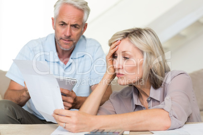 Concentrated mature couple with bills at home