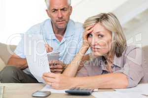 Tensed mature couple with bills at home