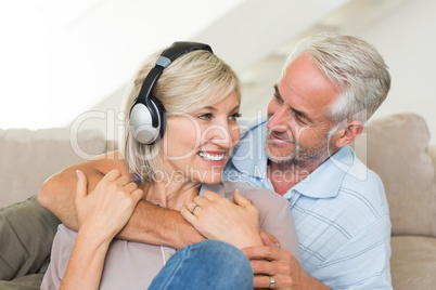 Mature man embracing woman from behind on sofa