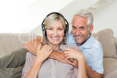 Mature man embracing woman from behind on sofa