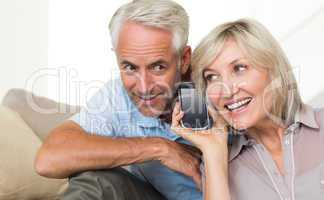 Mature couple using a smartphone on sofa