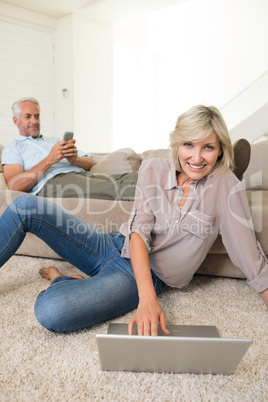 Couple with laptop and cellphone in living room at home