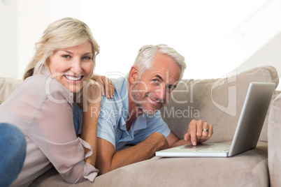 Happy mature couple using laptop on sofa Happy mature couple using laptop on sofa