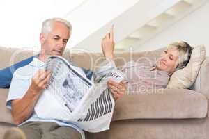 Couple with newspaper and cellphone in living room at home